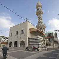 A man rides his bicycle past a mosque in the Circassian village of Kfar Kama in the northern Galilee region, on December 21, 2022. (Jalaa Marey/AFP)