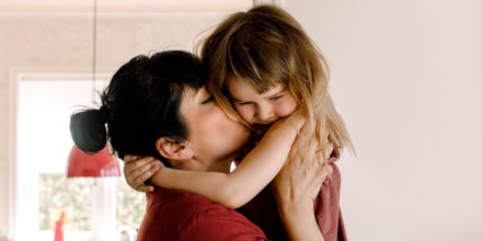 Side view of mother kissing sad daughter at home