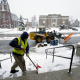 City worker Matt Houle, of Leominster, Mass., left, shovels the steps of Leominster City Hall, Tuesday, March 14, 2023, while a loader, behind, clears the street of snow, in Leominster. The New England states and parts of New York are bracing for a winter storm due to last into Wednesday. (AP Photo/Steven Senne)