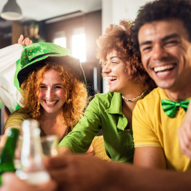 Multiethnic Group Of Young People Having Fun And Drinking Beer Together. Ireland national symbols. St Patricks Day.