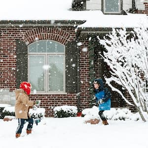 Two brothers playing with snow in front of their house