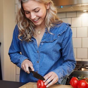 woman cutting up tomatoes in kitchen  