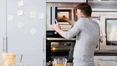 Man removing food from microwave while talking on phone