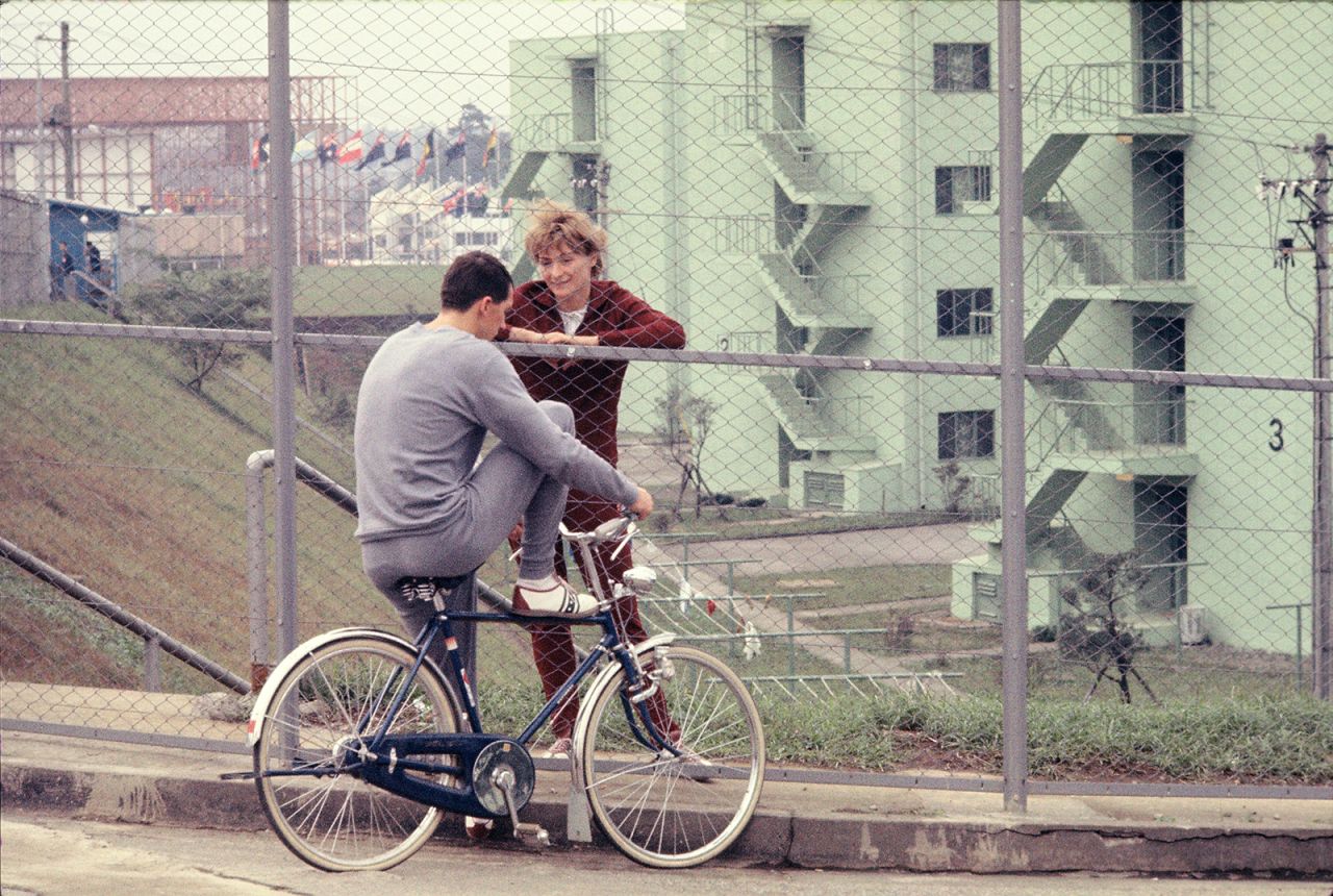 Athletes talk across a fence separating the male and female sections of the Olympic Village.