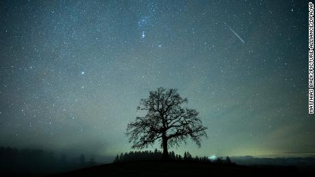 14 December 2020, Bavaria, M&#39;nsing: A shooting star can be seen during the Geminids meteor stream in the starry sky above a tree. The Geminids are the strongest meteor stream of the year. Photo by: Matthias Balk/picture-alliance/dpa/AP Images