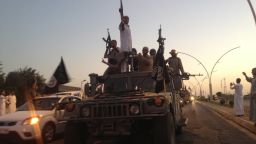 In this photo taken Monday, June 23, 2014, fighters of the al-Qaida-inspired Islamic State of Iraq and the Levant (ISIL) parade in a commandeered Iraqi security forces armored vehicle down a main road at the northern city of Mosul, Iraq.