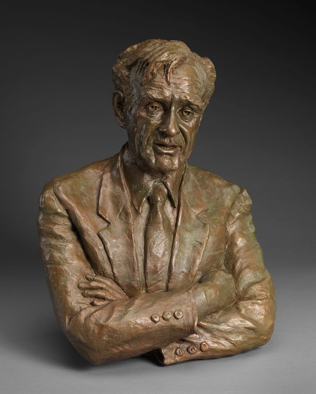 Bronze sculpture of Elie Wiesel. He is shown from the torso up with his arms crossed.