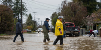 People walk through floodwaters in Watsonville, Calif., Friday, March 10, 2023.