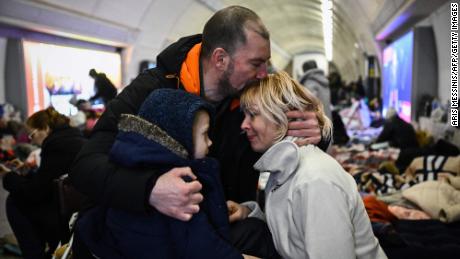 TOPSHOT - Sergyi Badylevych (C), 41, hugs his wife Natalia Badylevych (R), 42, and baby in an underground metro station used as bomb shelter in Kyiv on March 2, 2022. - On the seventh day of fighting in Ukraine Russia claims control on March 2, 2022 of the southern port city of Kherson, street battles rage in Ukraine&#39;s second-biggest city Kharkiv, and Kyiv braces for a feared Russian assault. (Photo by Aris Messinis / STF / AFP) (Photo by ARIS MESSINIS/STF/AFP via Getty Images)