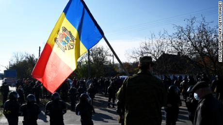 A man holds Moldovan national flag as special police officers patrol a street near a polling station during the second round of Moldova&#39;s presidential election in the town of Varnita at Moldova - Transnistrian border on November 15, 2020, amid the ongoing Covid-19 pandemic.
