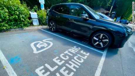 Electric cars are charged by a wall charger in a city centre car park, on July 15, 2022 in Bath, England. The government&#39;s commitment to reducing future Co2 carbon emissions will mean many more motorists will need to switch from petrol and diesel powered cars to electric (EV) driven ones. However there are also fears that the charging network in the UK is not yet fit to deal with the enormous demand more EVs on the road would place on it.
