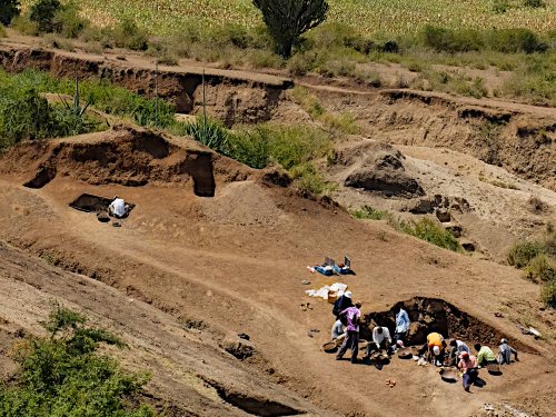 Expansive plains with a group of 10 people excavating large dirt holes