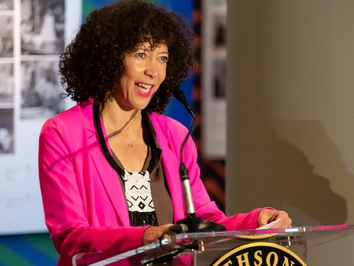 Woman in pink blazer speaks at podium with Smithsonian Institution logo