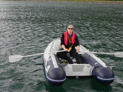 Person rowing boat on a body of water pauses to look straight ahead