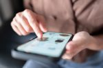 A SEATED PERSON HOLDS A SMARTPHONE, SHOPPING