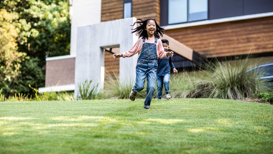 Brother and sister running in the front yard