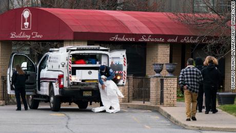 ANDOVER, NJ - APRIL 16: Medical workers put on masks and personal protective equipment (PPE) while preparing to transport a deceased body at Andover Subacute and Rehabilitation Center on April 16, 2020 in Andover, New Jersey. After an anonymous tip to police, 17 people were found dead at the long-term care facility, including two nurses, where at least 76 patients and 41 staff members have tested positive for COVID-19. (Photo by Eduardo Munoz Alvarez/Getty Images)