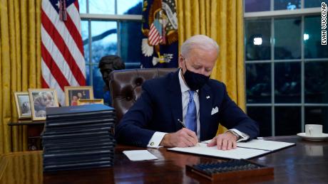 President Joe Biden signs his first executive orders in the Oval Office of the White House on Wednesday, Jan. 20, 2021, in Washington. 