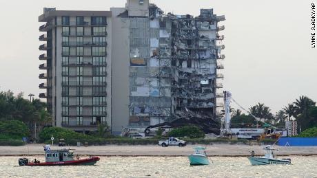 A U.S. Coast Guard, left, and a Miami-Dade County Police boat, right, patrol the ocean in front of the partially collapsed Champlain Towers South condo building, where demolition experts were preparing to bring down the precarious still-standing portion, Sunday, July 4, 2021, in Surfside, Fla. The demolition work has suspended the search-and-rescue mission in the rubble below, but officials said it should eventually open up new areas for rescue teams to explore.