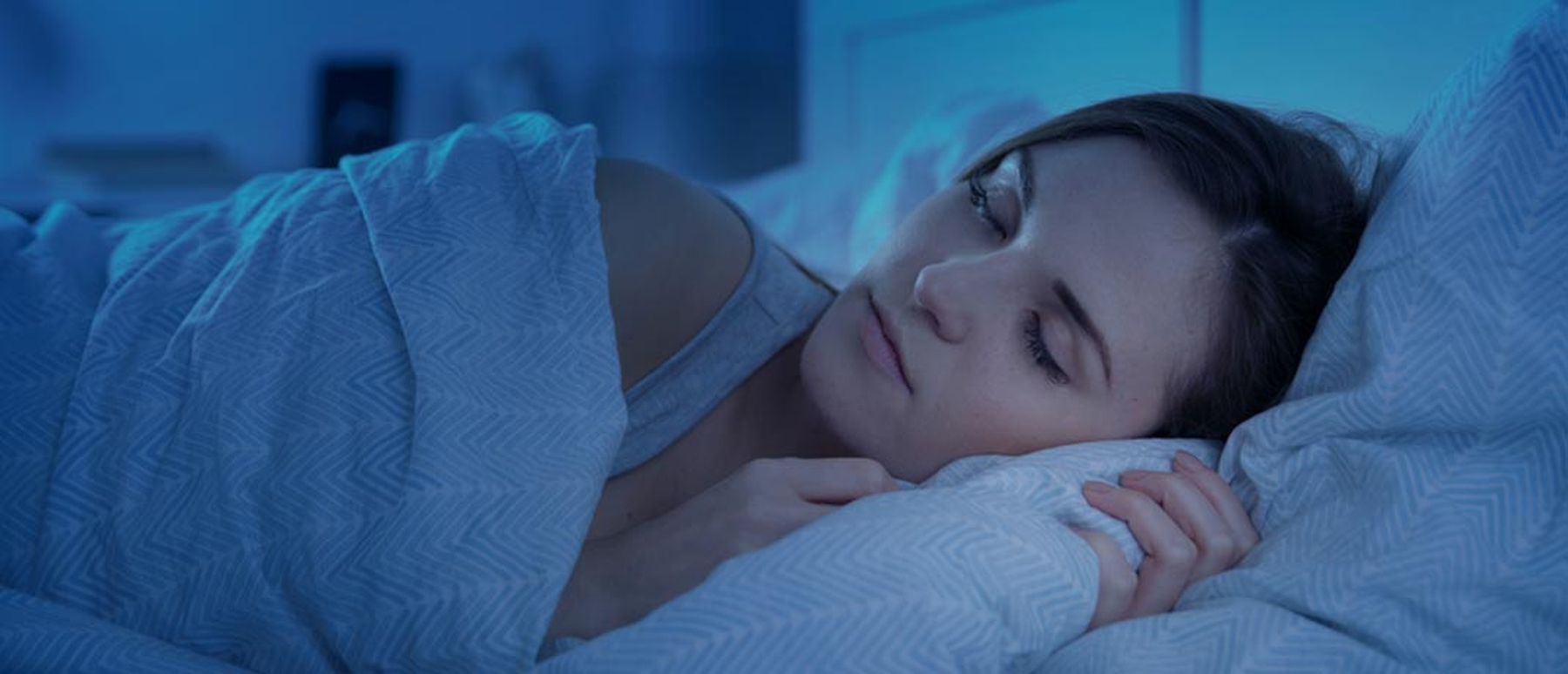 Woman in a dark room sleeping in a bed