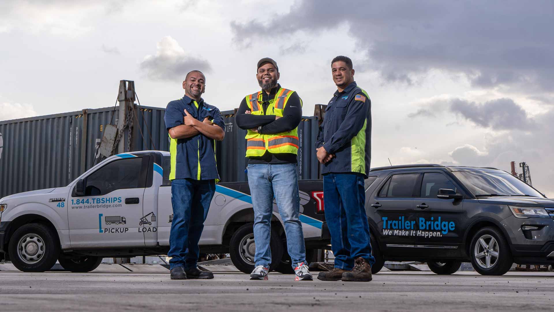 Image Three Trailer Bridge Employees Smiling In Front of Cars