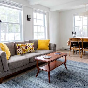 Bright living room with gray sofa and dining table