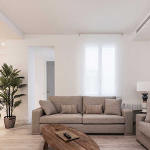 A spacious living room with an air duct above the sofa