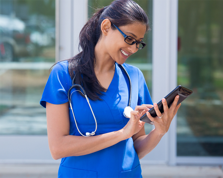 Latina doctor smiling as she reads information on her tablet