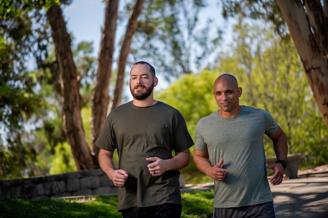 Two young Veterans jog through a park.