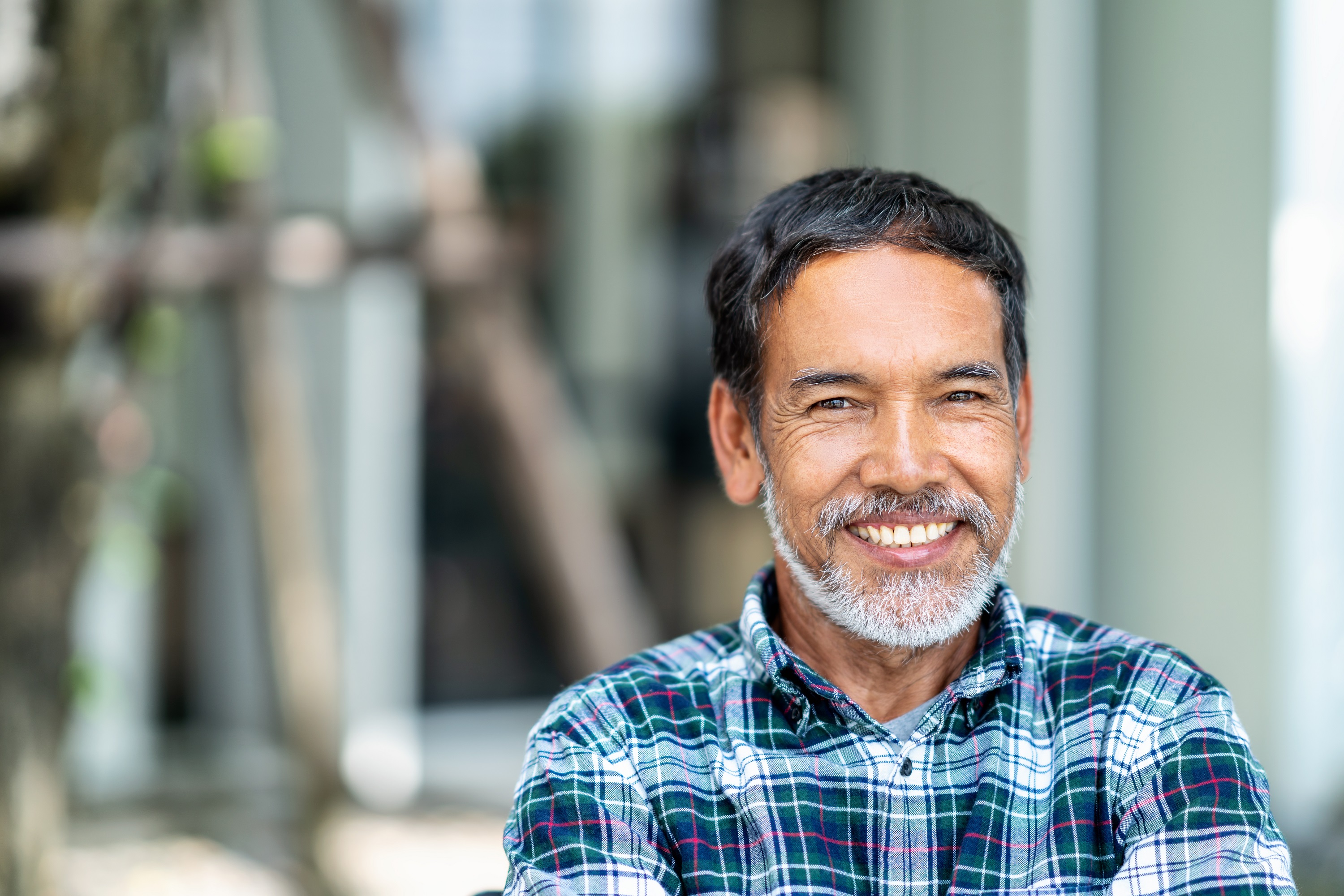 A smiling, middle-aged Veteran stands in front of his home.