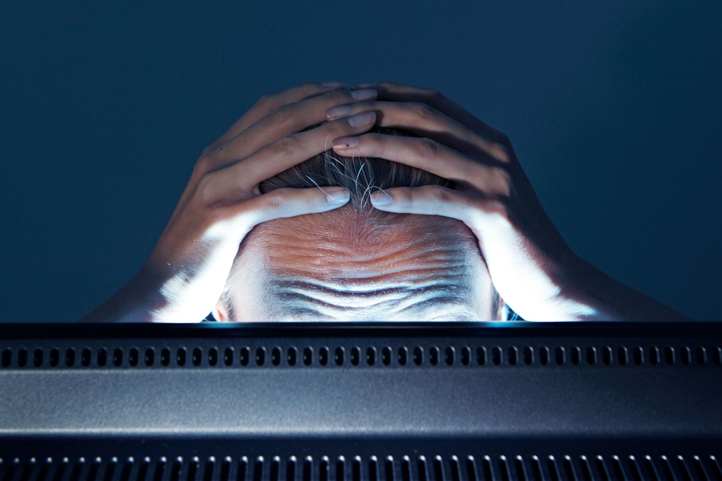 Stressed person behind computer screen