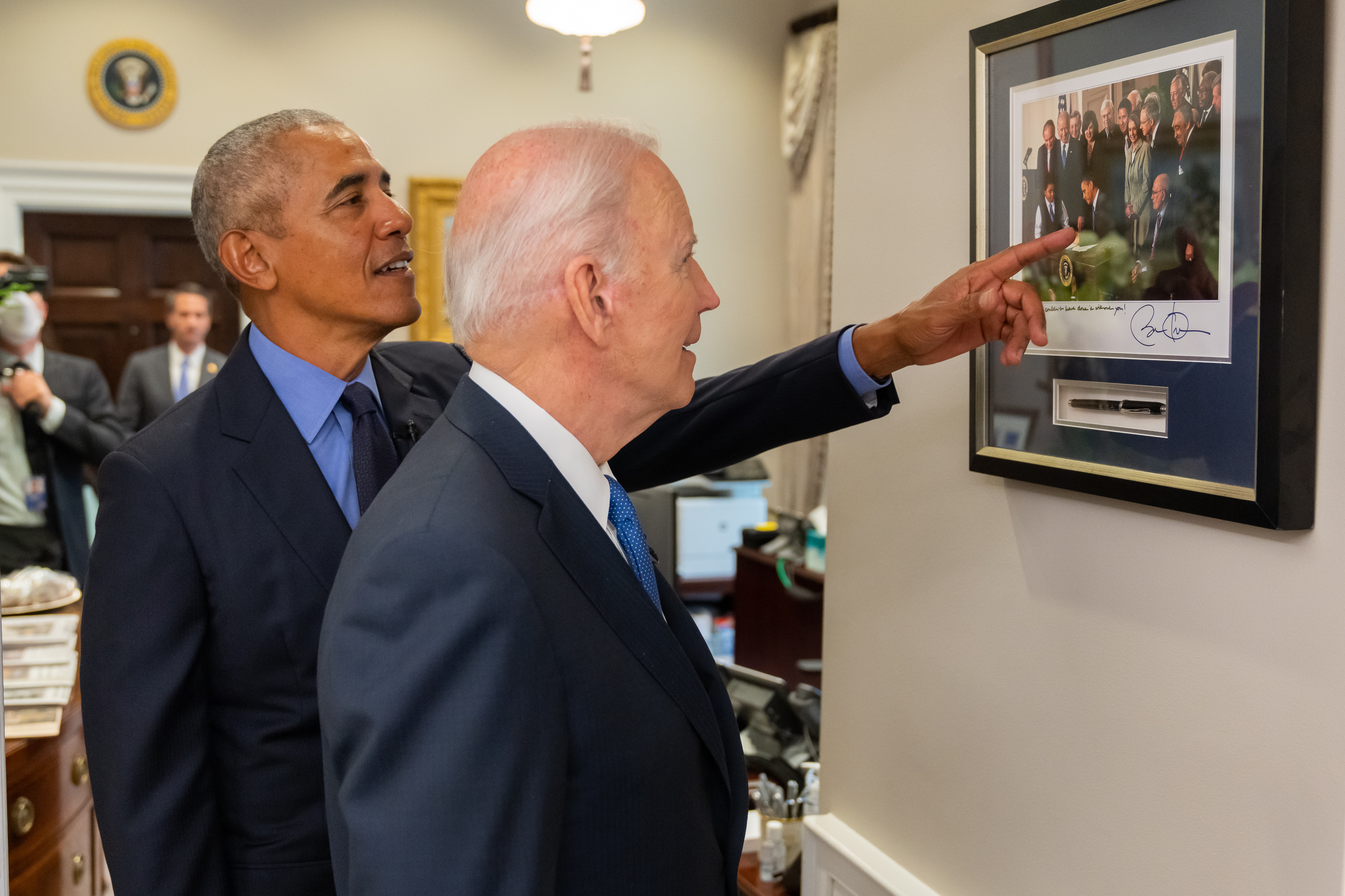 President Biden and Former President Obama look at a photograph from the day that the Affordable Care Act was signed.