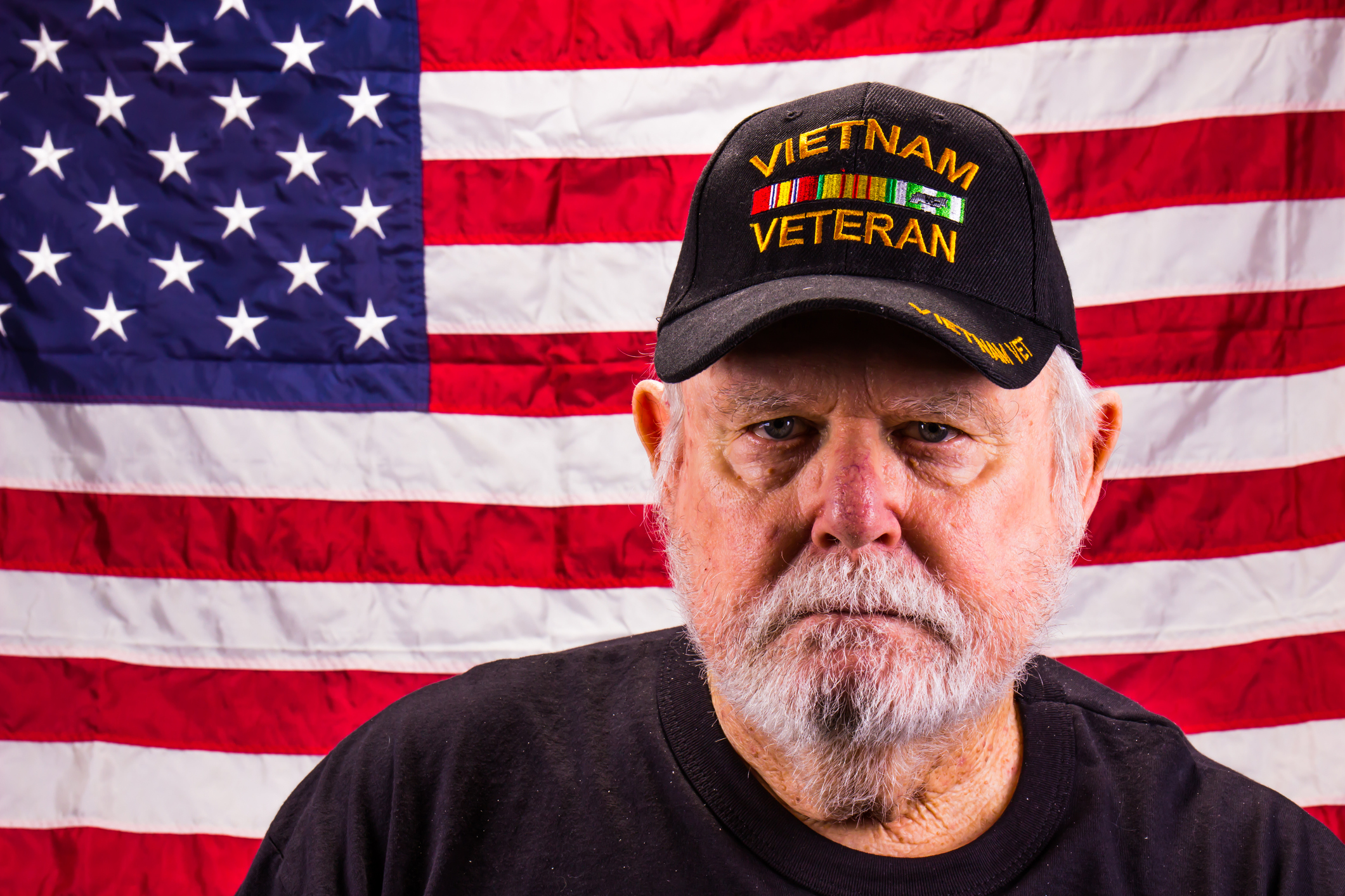 Vietnam vet looking sternly at camera, with American flag in background