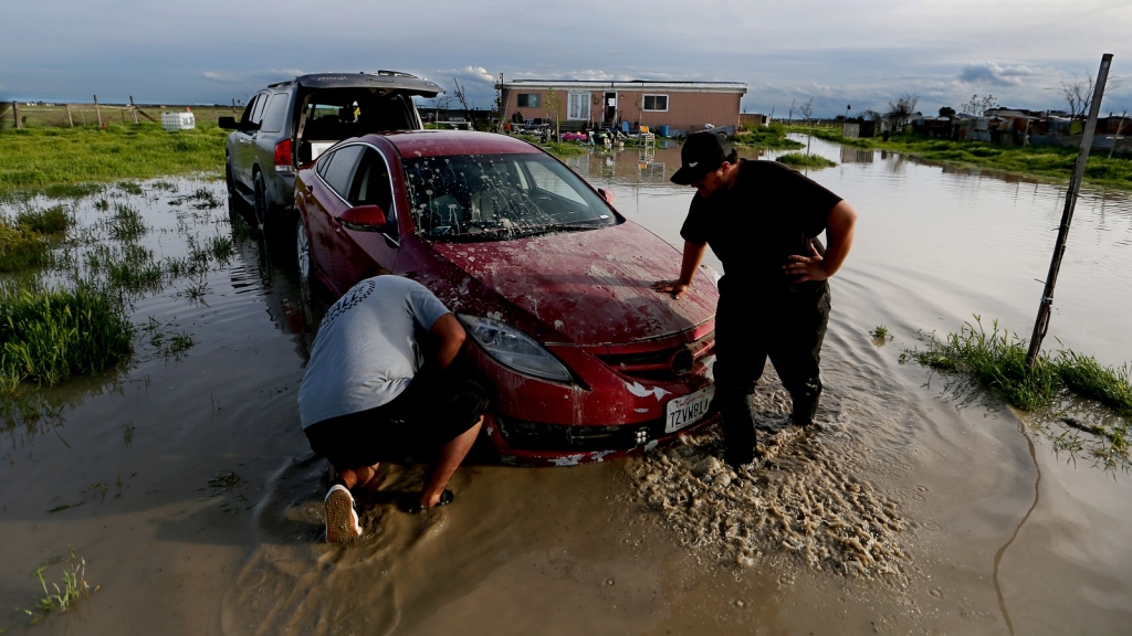 Jairo Estrada, left, and Juan Espinoza work to get one of their family's car off their flooded property in Allensworth, California. Portions of the town have flooded as Tulare Lake reappears.