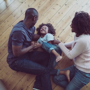Parents tickling son on hardwood floor