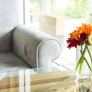 A vase with flowers on a wooden table with a glass tabletop