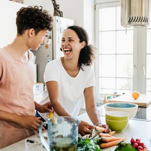 A mother laughing while preparing lunch with her son