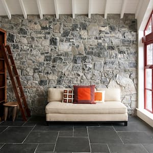 A living room with a stone wall behind the sofa