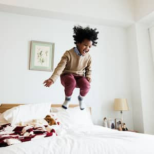 Boy having fun jumping on bed