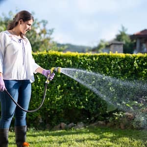 A woman watering garden with hose
