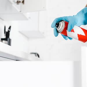 Man using gloves sprays inside kitchen cabinets