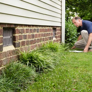 Foundation inspector looking at a brick foundation with vents