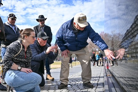 Veterans from Alpha Company, 3rd Battalion, 506th Infantry Regiment, along with family and friends, search for the names of the men from their company who lost their lives in the Vietnam War. 