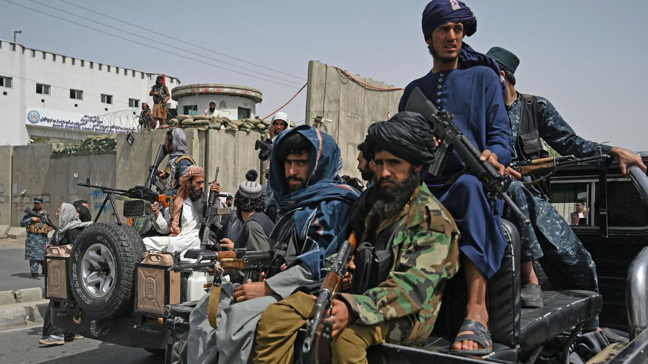 TOPSHOT - Taliban fighters escort veiled women marching during a pro-Taliban rally outside the Shaheed Rabbani Education University in Kabul on September 11, 2021.