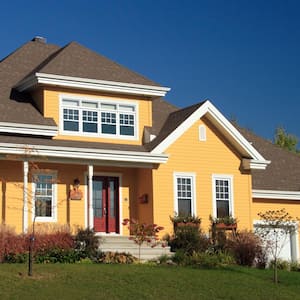 The exterior of a yellow house with a nice roof