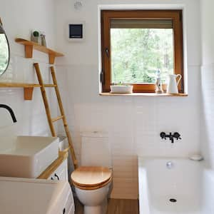 shot of small bathroom with white tile, white sink, bathtub and toilet, and tan accents