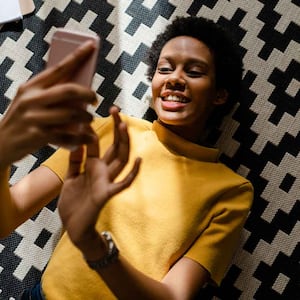 A woman using her smartphone while lying down on the carpet