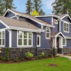 Home exterior with green lawn and forest in background