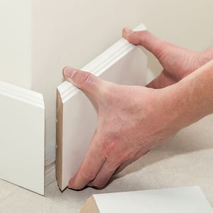 Hands installing baseboard