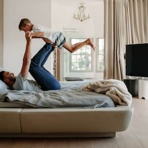 Father and son playing around in modern master bedroom